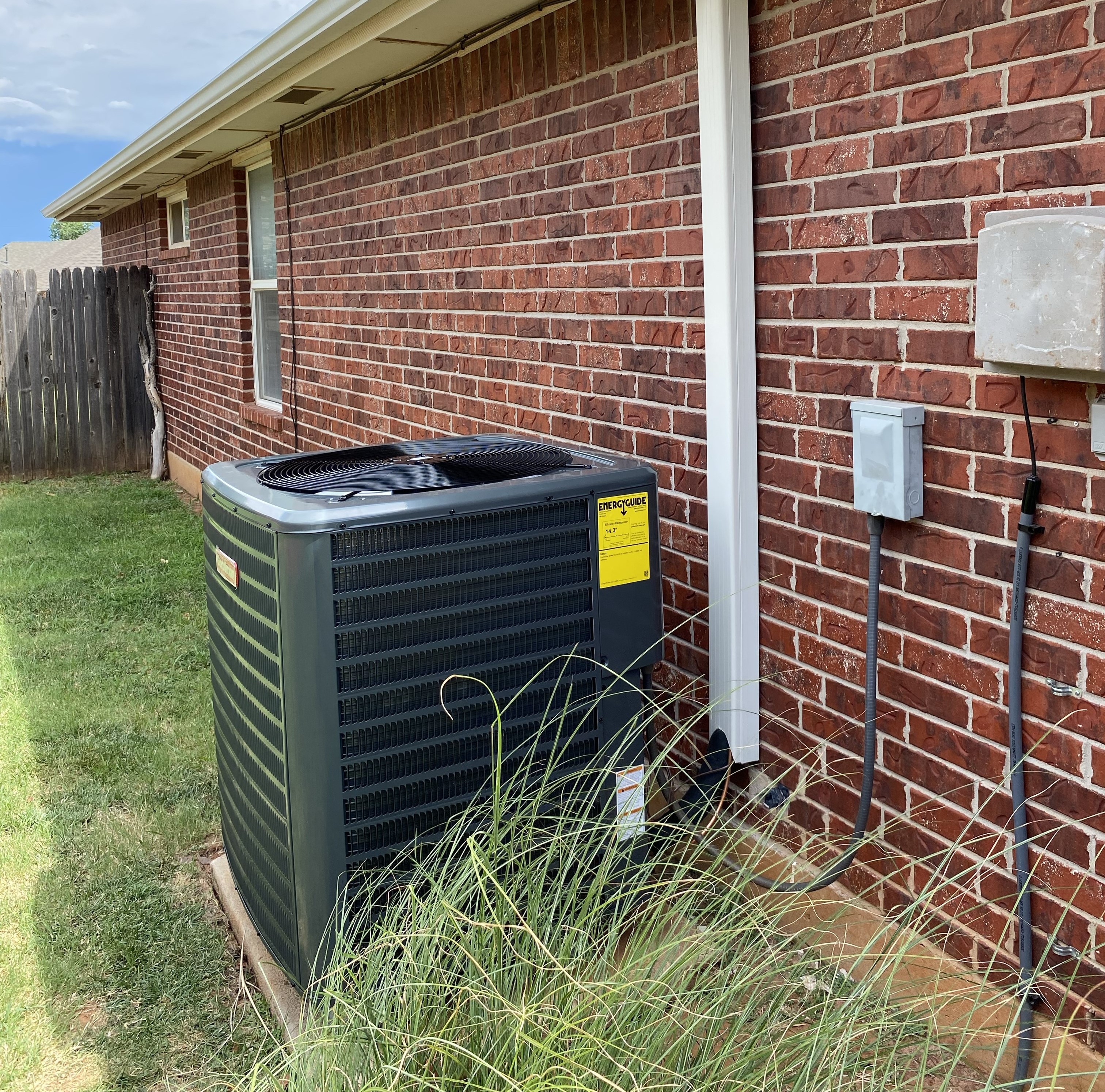 Two outdoor central air conditioning units installed on concrete pads next to a building, ready for operation.